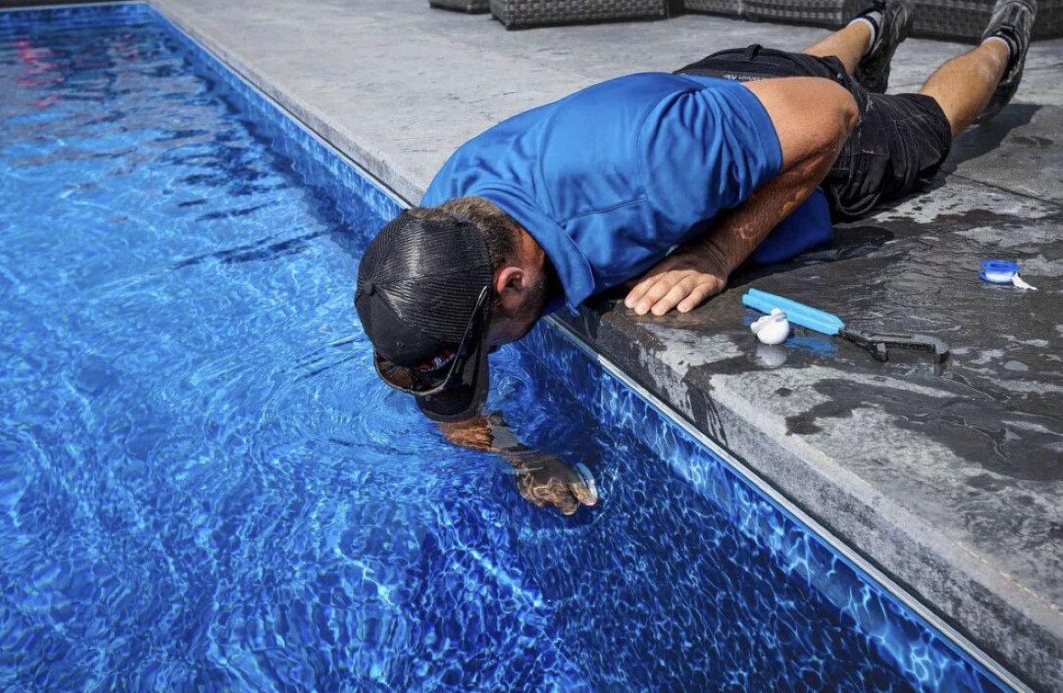 Professional pool technician removing calcium scale and cleaning pool tile in Paramount, CA